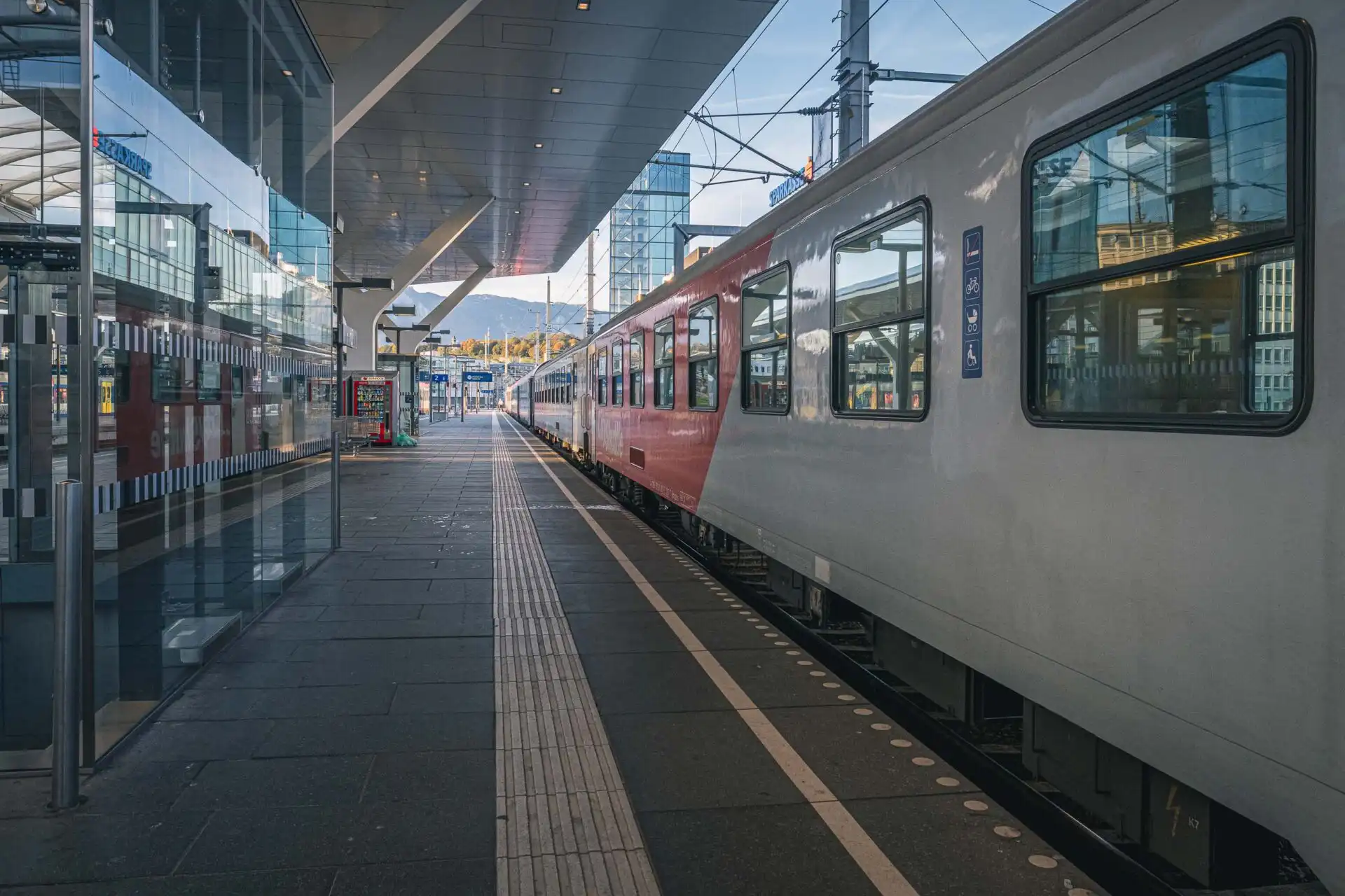 Red train under the glass canopy at Salzburg Hauptbahnhof