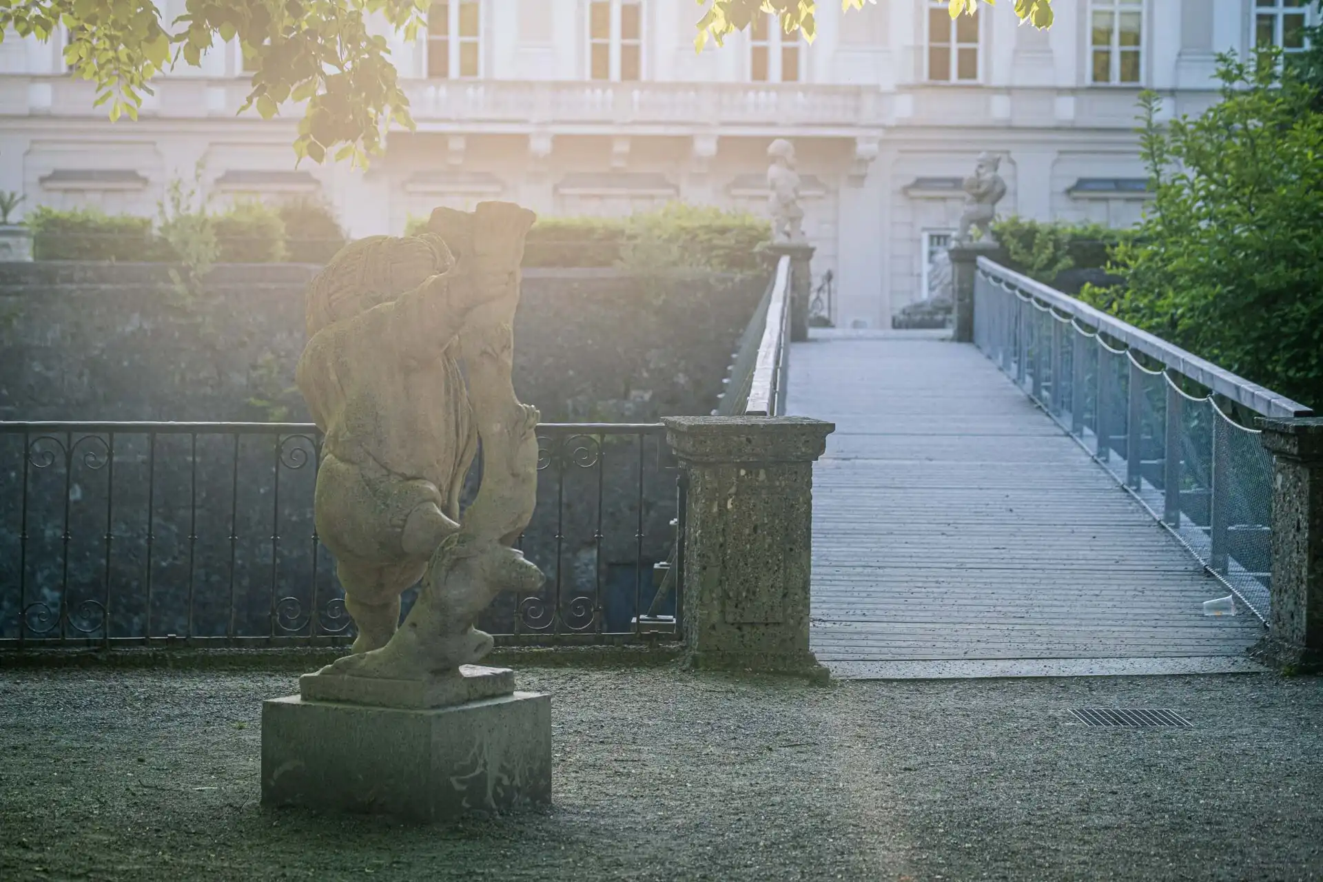 Stone dwarf statue beside a footbridge at the Zwerglgarten in Mirabell Gardens