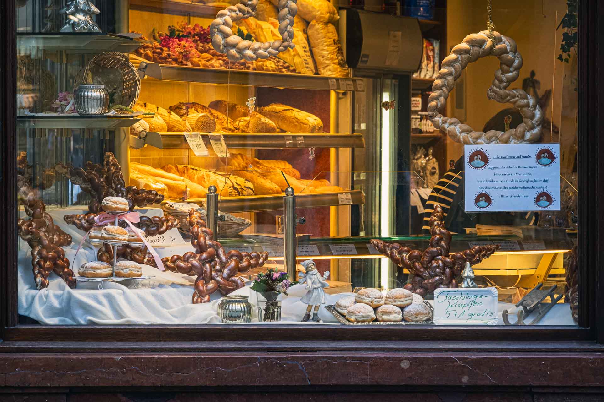 A bakery window display showcasing a variety of breads, pastries, and pretzels.
