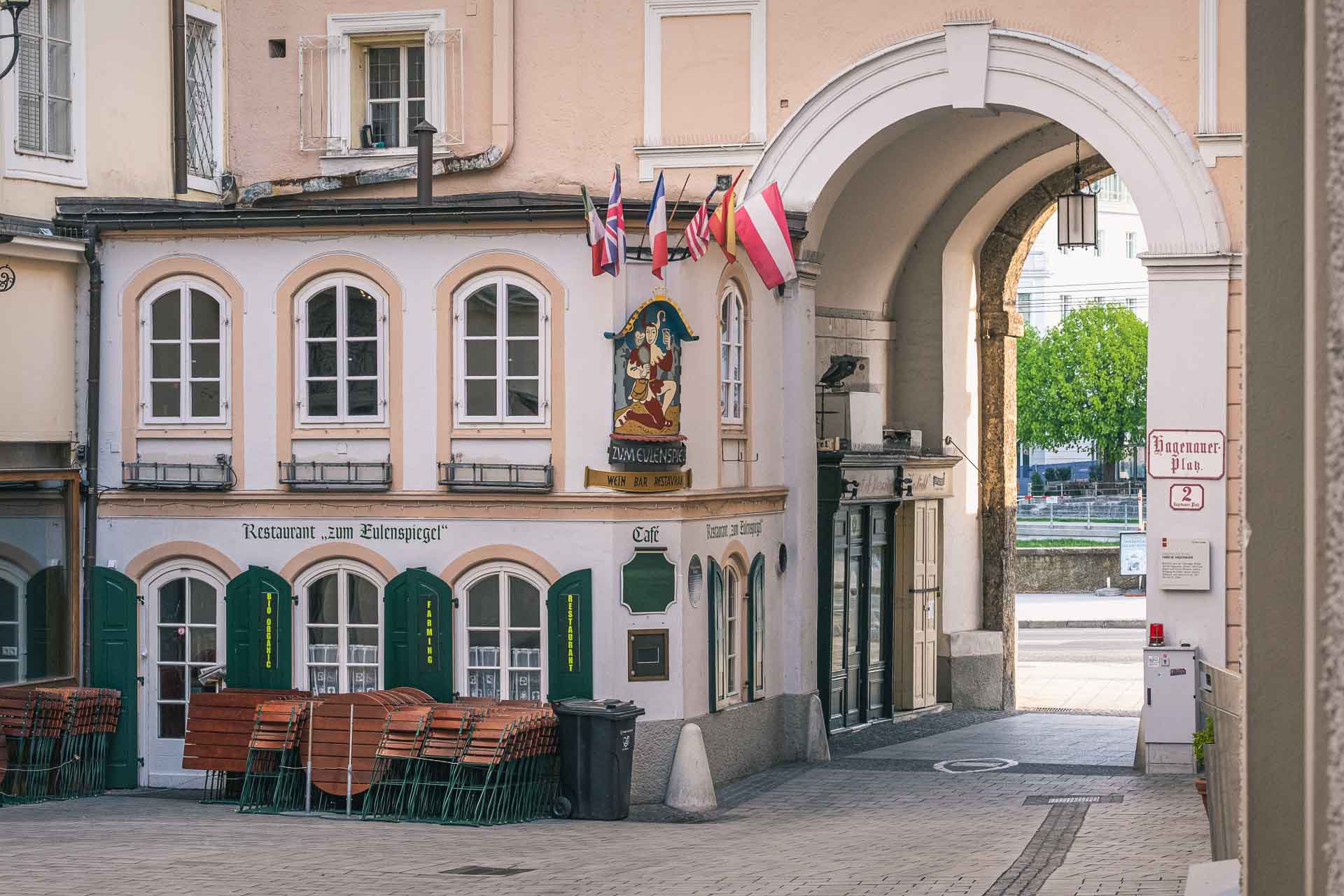 An archway leading to a building with tables and chairs.